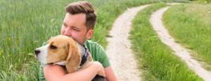 Man hugging dog on rural road