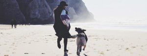 woman and dog running on the beach